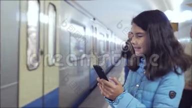 少女在地下地铁里乘地铁等待火车的到来，手持智能手机.. 一点点